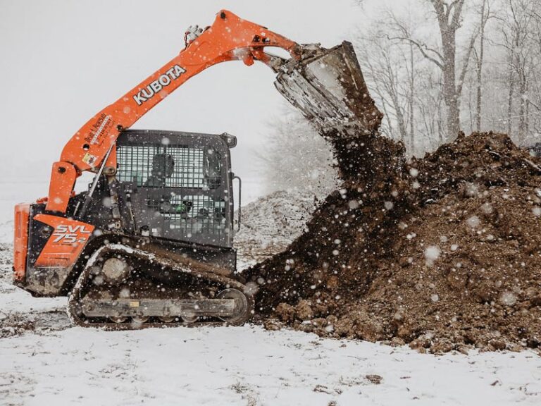Excavator skimming off topsoil for new home construction